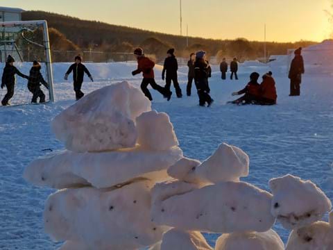 barn som spelar fotboll på skolgård på vintern