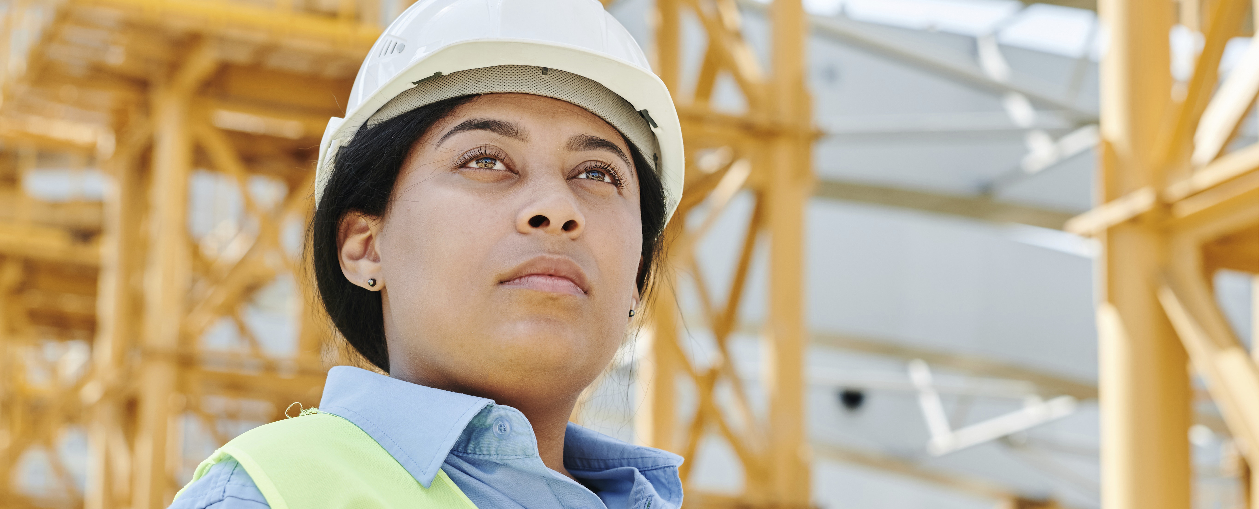 bild som visar mörkhårigkvinna med hjälm på byggarbetsplats