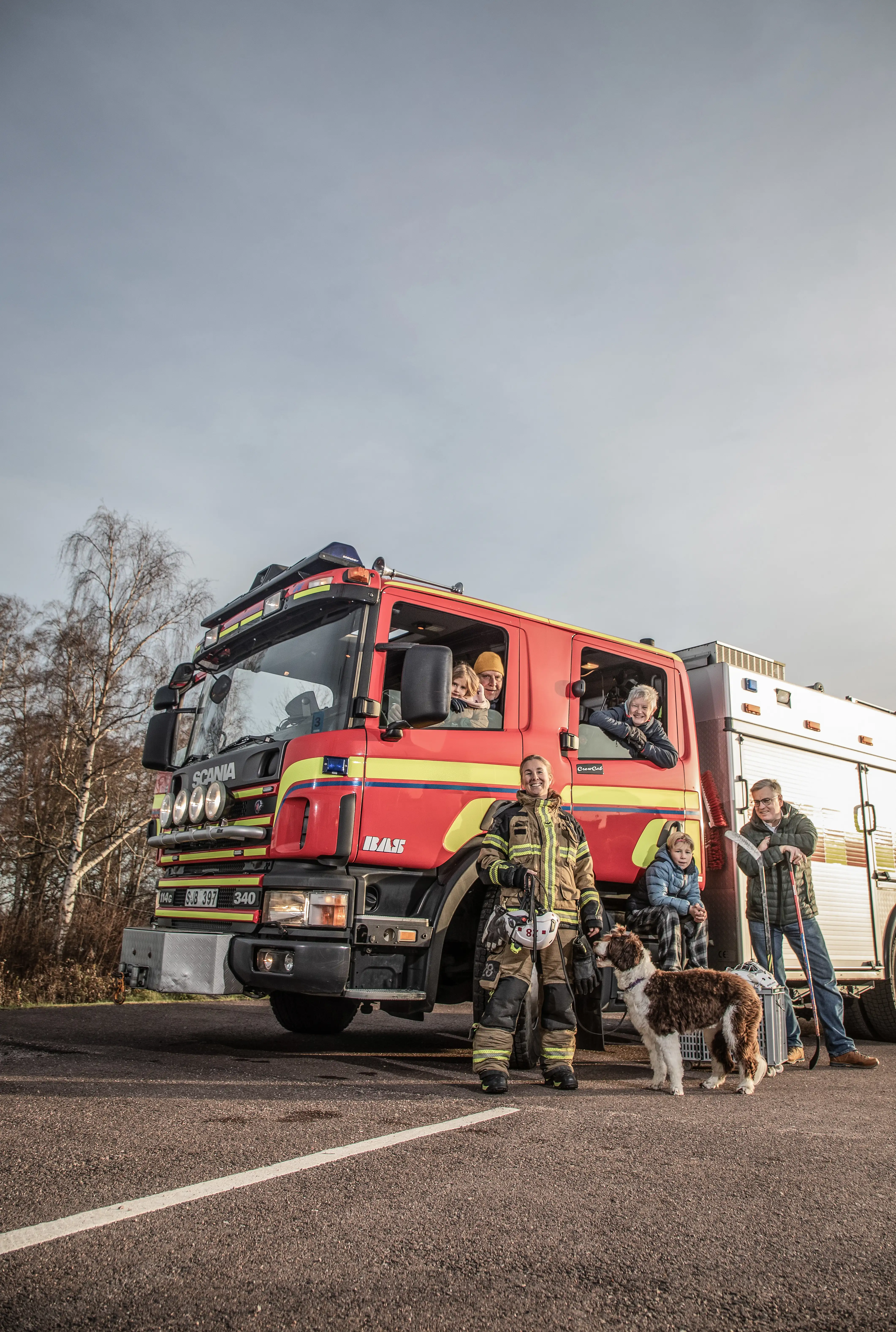 familj med hund står framför en brandbil