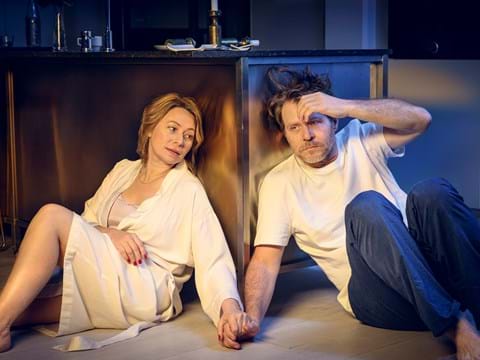 en kvinna och en man sitter på golvet och hållar varandra i handen