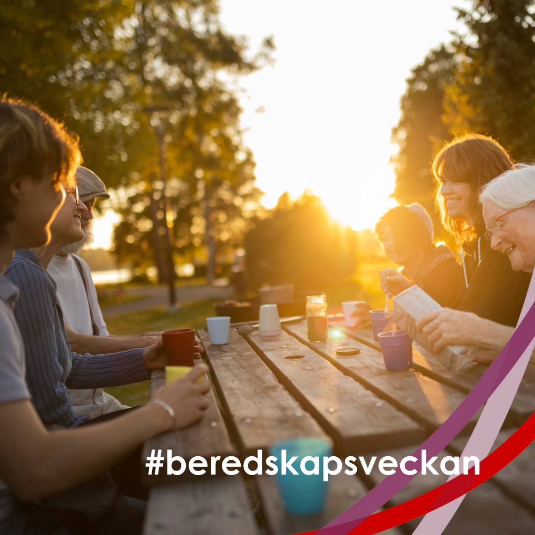människor sitter vid ett bord utomhus i motljus, gröna träd och solen i bakgrunden