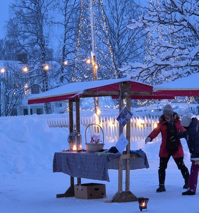 ett marknadsbord i skymningsljus utomhus under julmarknaden