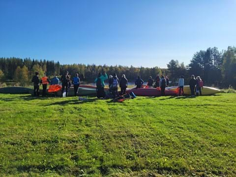 Elever och kanoter på en grön äng inför paddling