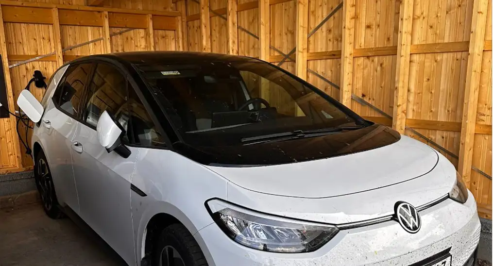 bilden visar en vit elbil i en carport