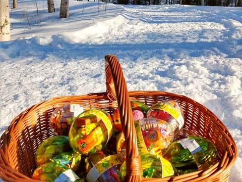 bilden visar fyllda godisägg i en korg utomhus i skogen med snö på marken