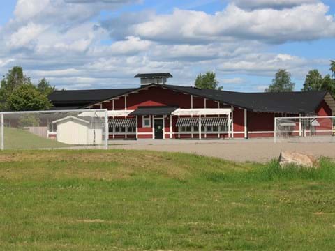 en röd enplans skolbyggnad med gräsmatta och fotbollsmål framför
