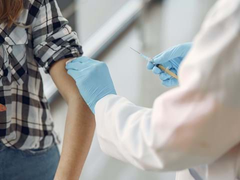 en person får en vaccintationsspruta i armen av sjukvårdspersonal