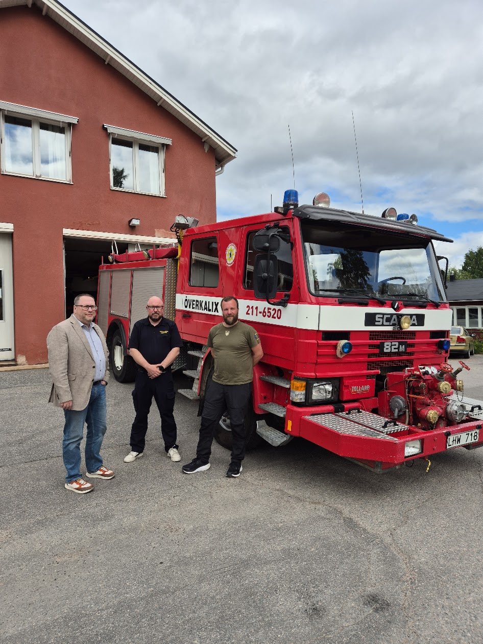 Tre män framför en brandbil