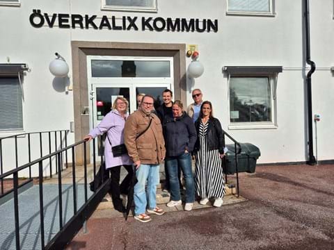 en grupp människor står samlade utanför entrén till kommunhuset