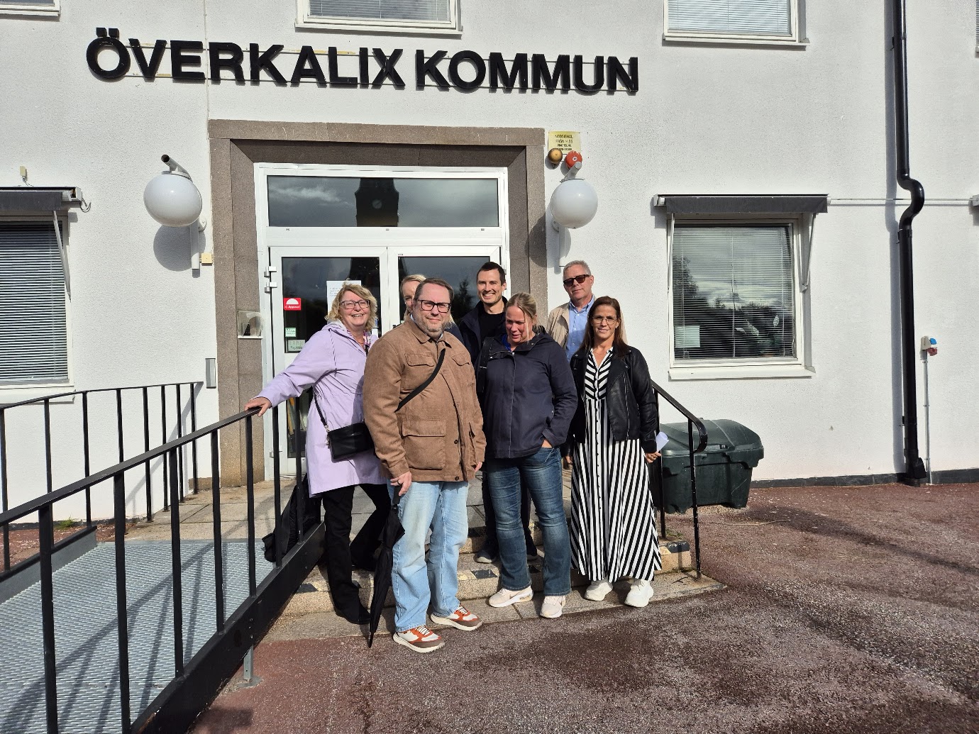 en grupp människor står samlade utanför entrén till kommunhuset