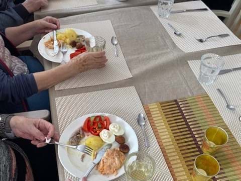 bild på dukat bord med påskbuffé, vita tallrikar med mat och händer på personerna som sitter till bords