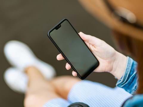bilden visar en mobiltelefon i handen på en sittande person