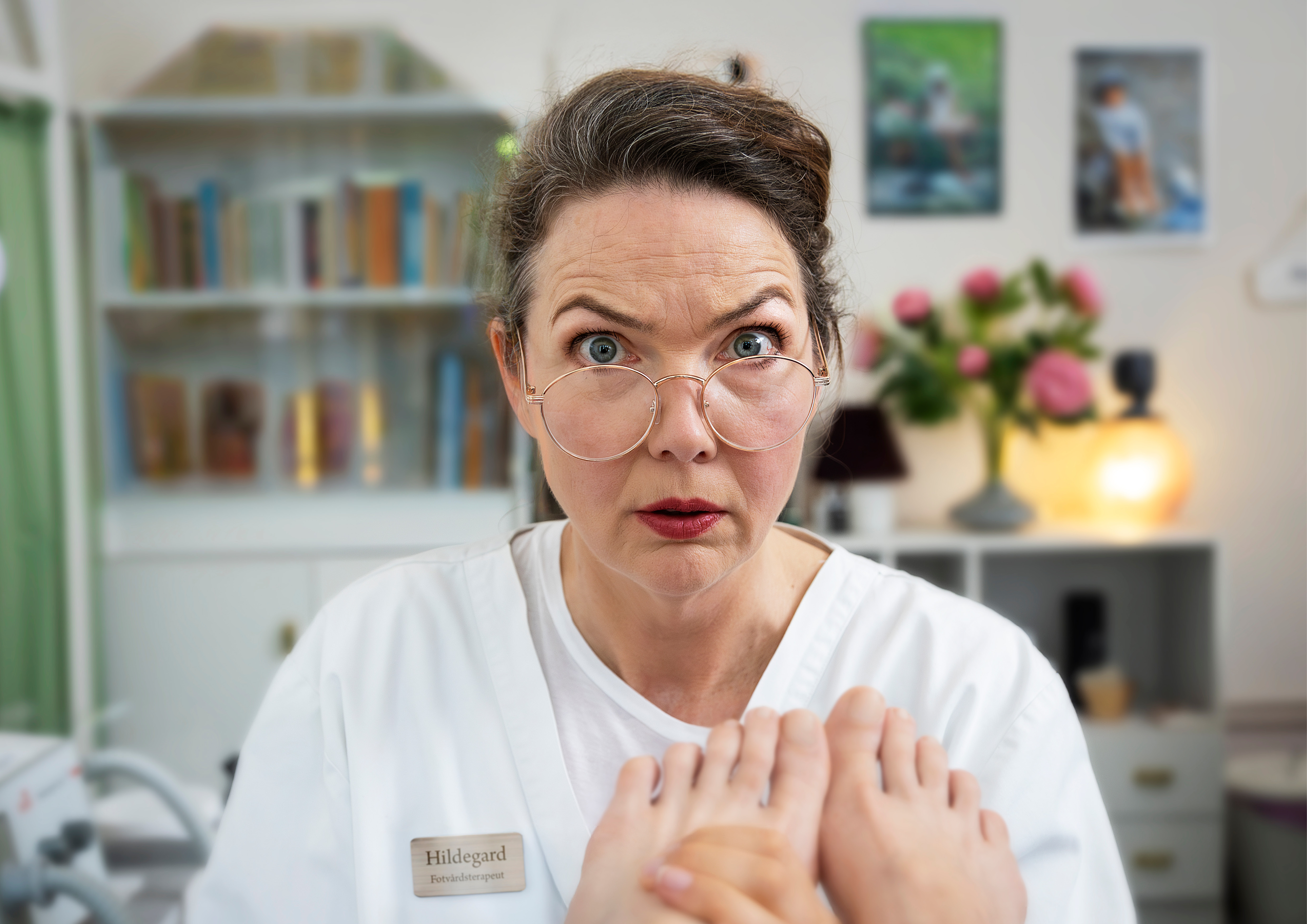 en kvinna i vit tröja och glasögon tittar in i kameran