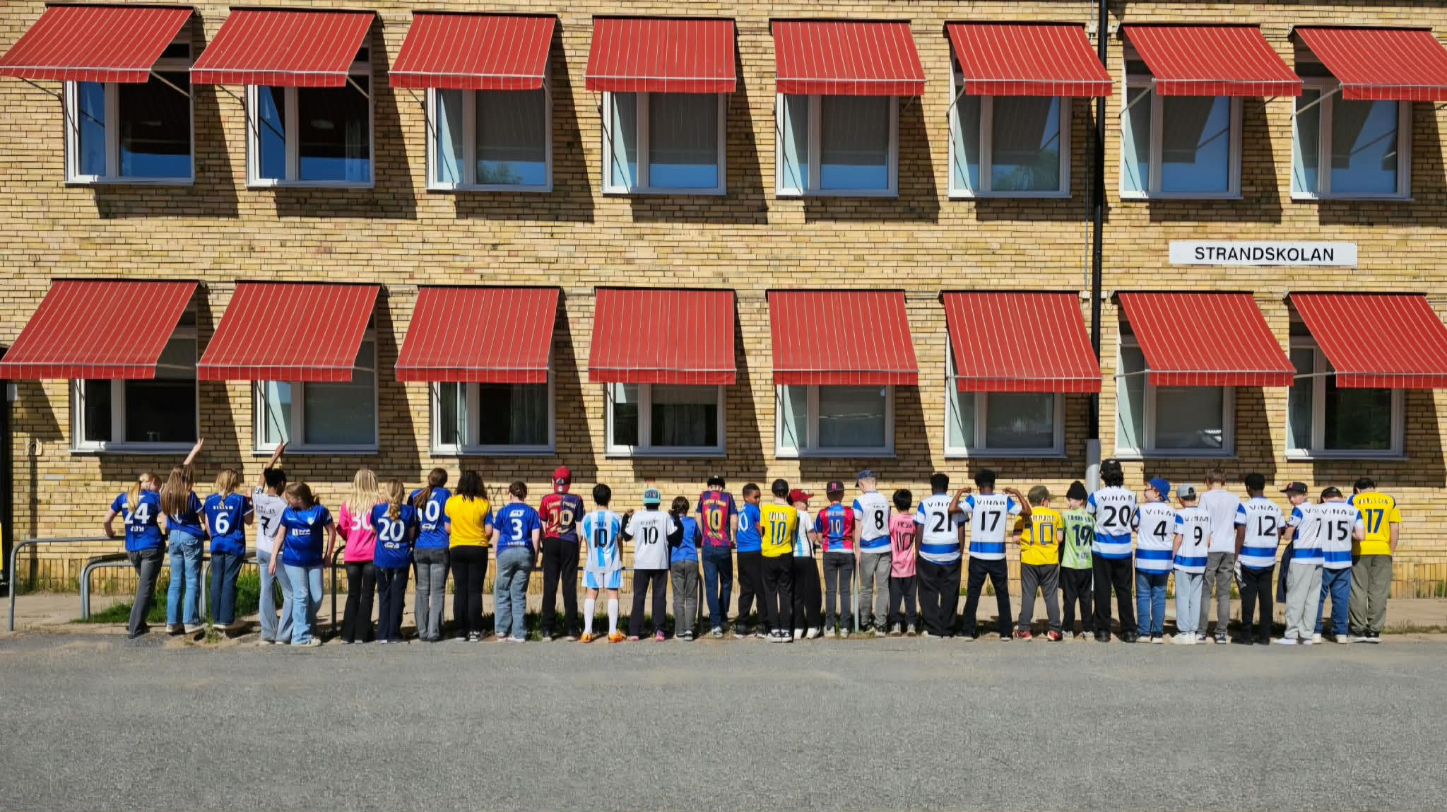 barn i fotbollströjor står utanför en skola